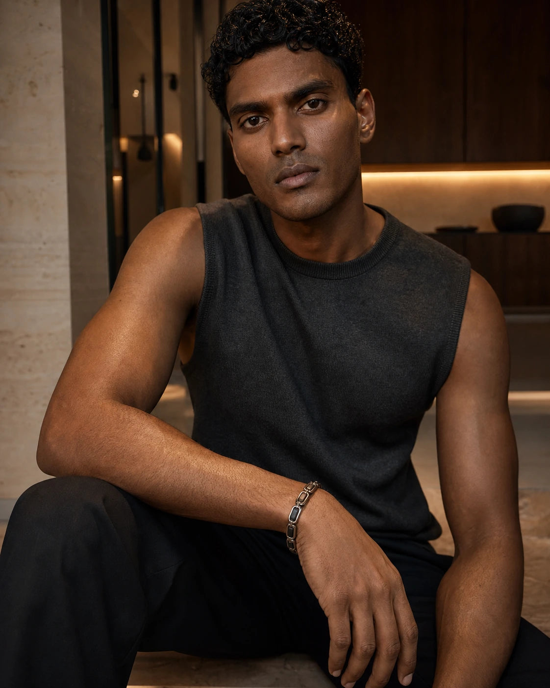 South Asian male model wearing the DARENZ Continuum Link Bracelet with alternating blackened steel links in a warm limestone residence