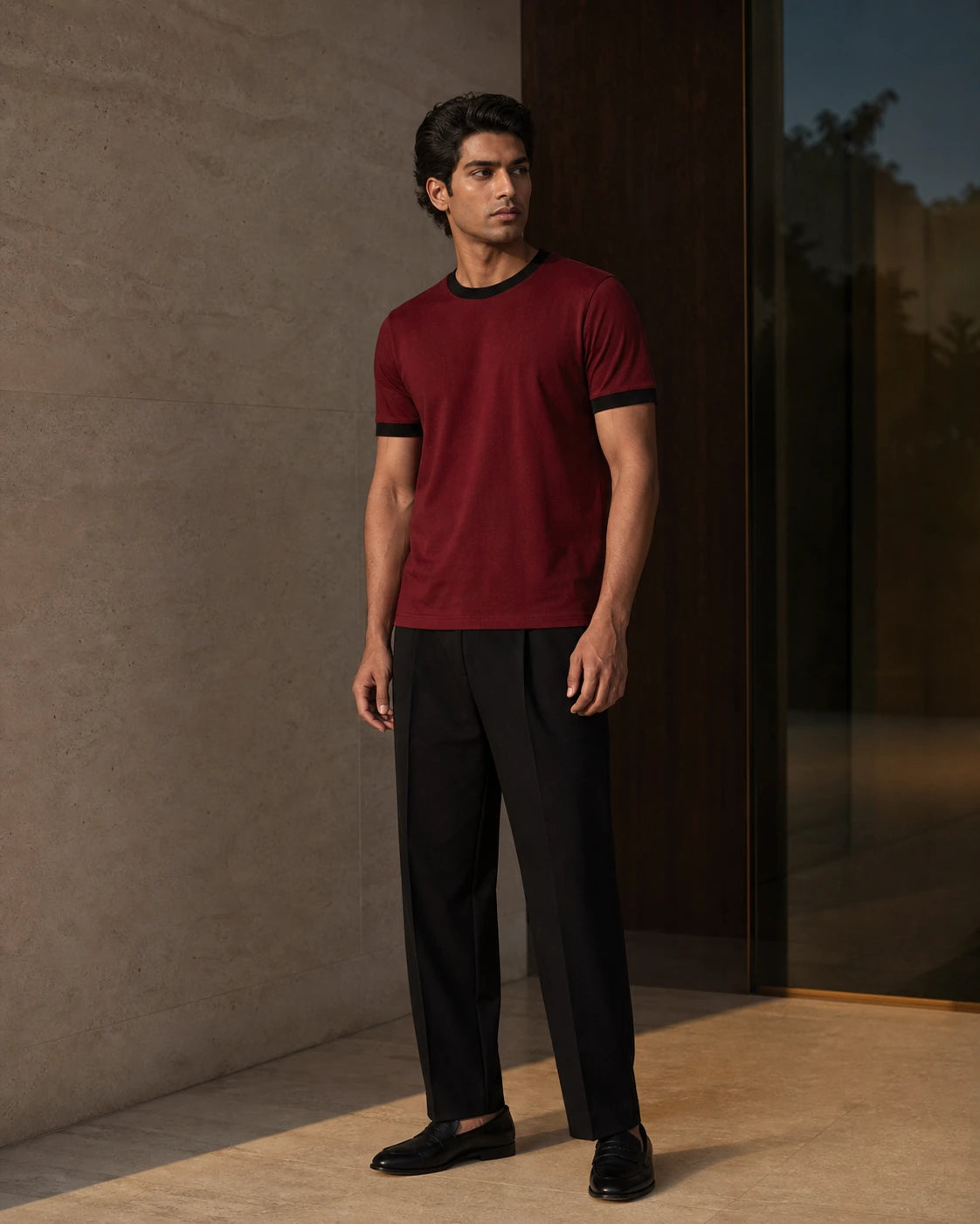 South Asian male model wearing the DARENZ First Line Ringer Tee in Cardinal / Black, full-length front view in a warm limestone residence