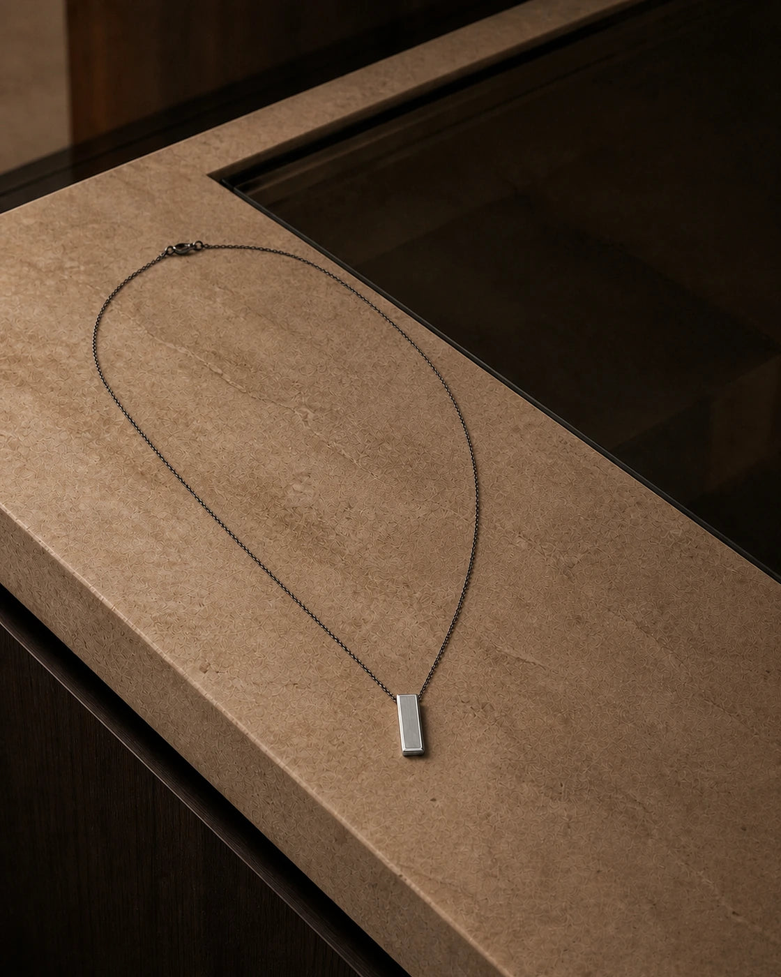 DARENZ Footnote Pendant still life on charcoal stone with dark timber and controlled evening light