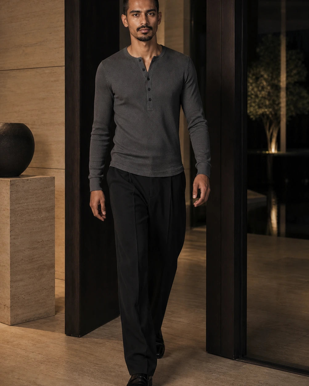 DARENZ Interval Long-Sleeve Henley in Graphite shown in motion beside dark timber, with the garment drape clearly visible