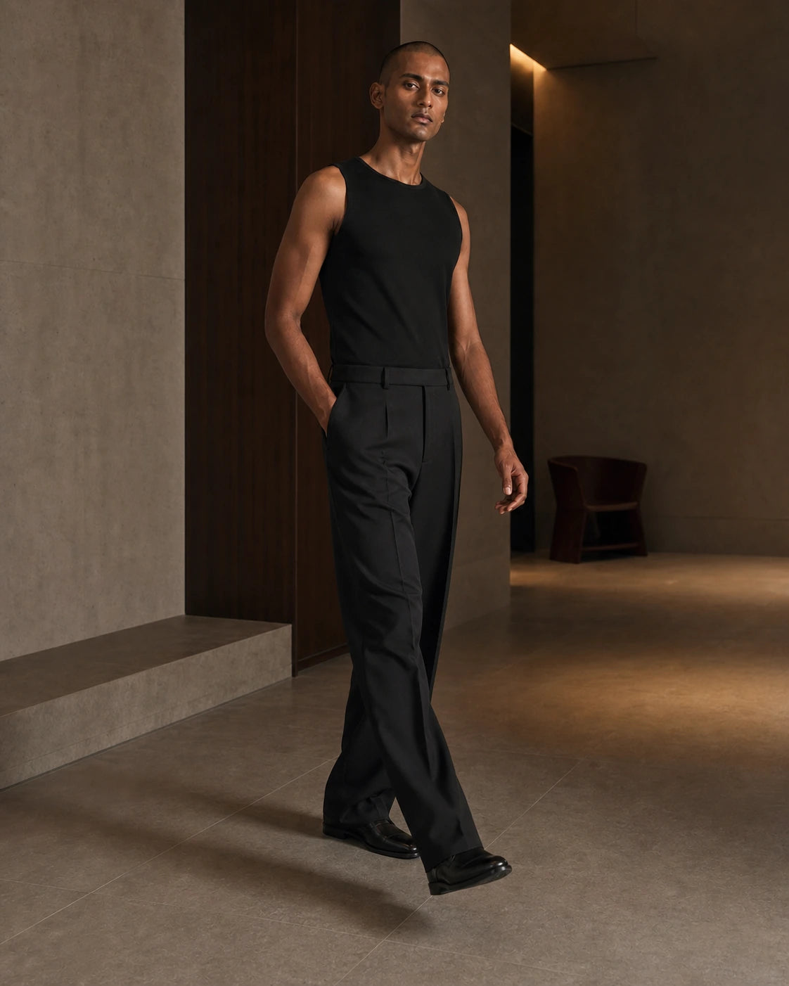 DARENZ Long Form Loose Tailored Trousers in Ink shown in motion beside dark timber, with the garment drape clearly visible
