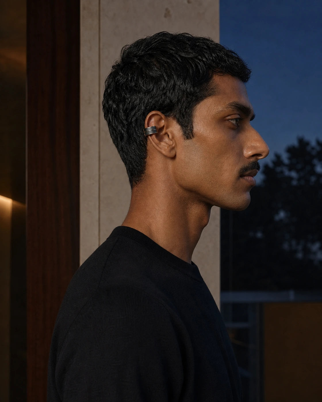 Scale and fit view of the DARENZ Margin Ear Cuff on its assigned model beside smoked glass