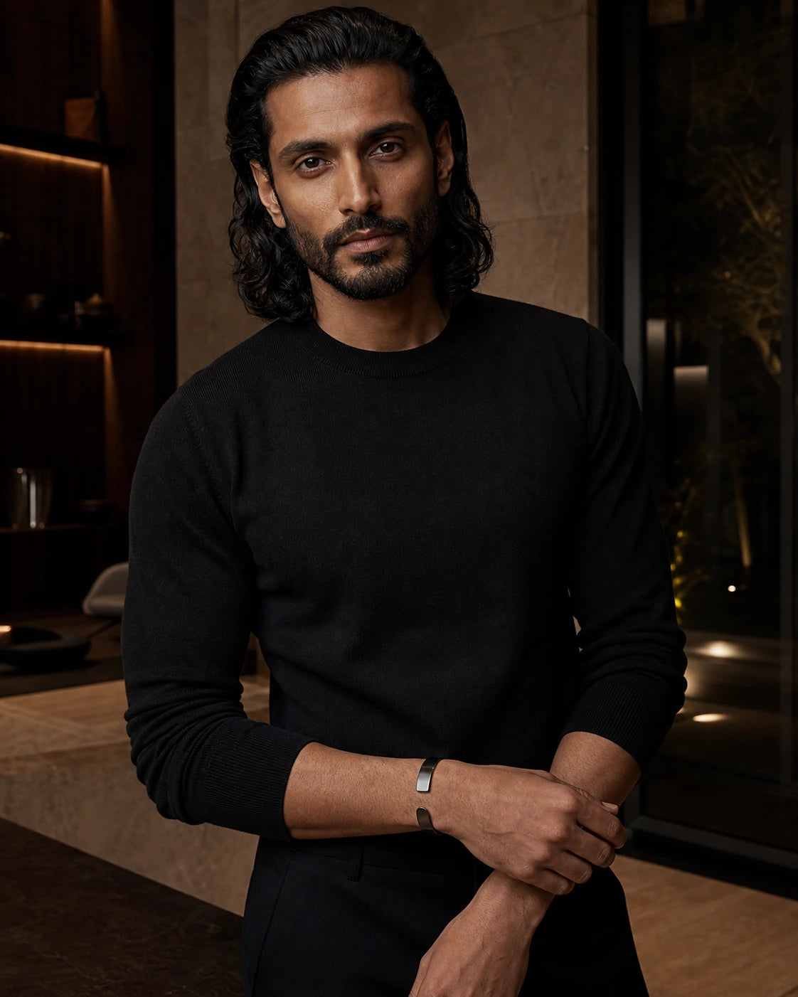 South Asian male model wearing the DARENZ Parenthesis Cuff in blackened steel, styled in a warm limestone residence