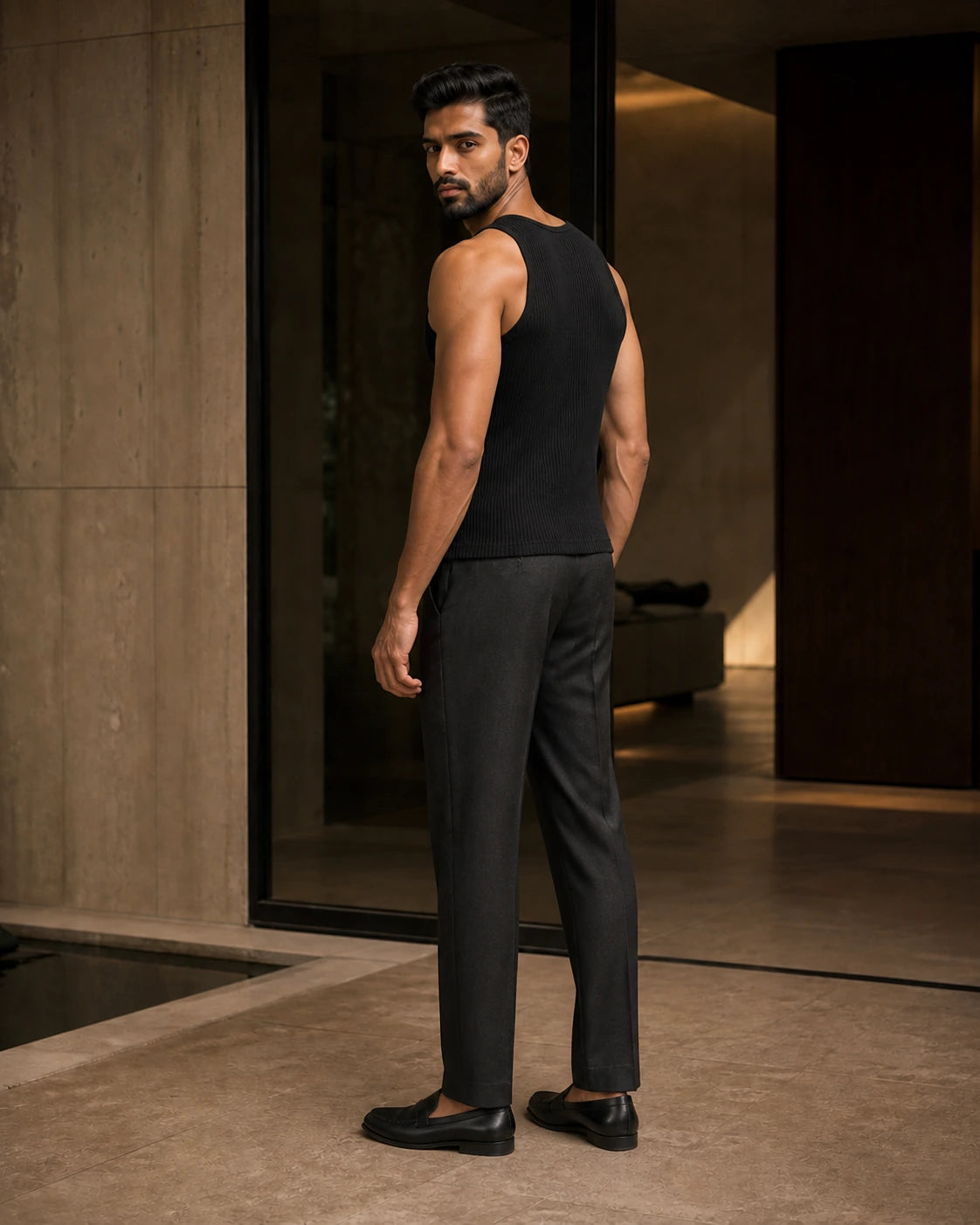 Side and back view of the Black DARENZ Underline Ribbed Vest on its assigned model near smoked glass